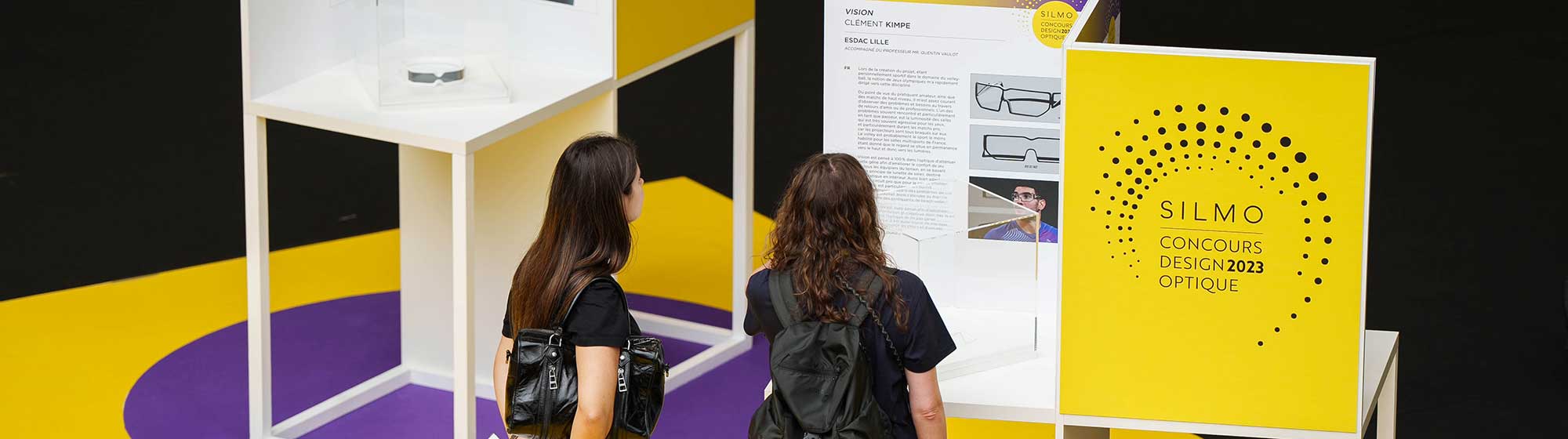 Deux femmes devant le panneau du Concours de design optique 2023