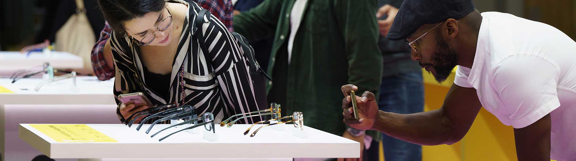 A man and a woman looking at and photographing glasses