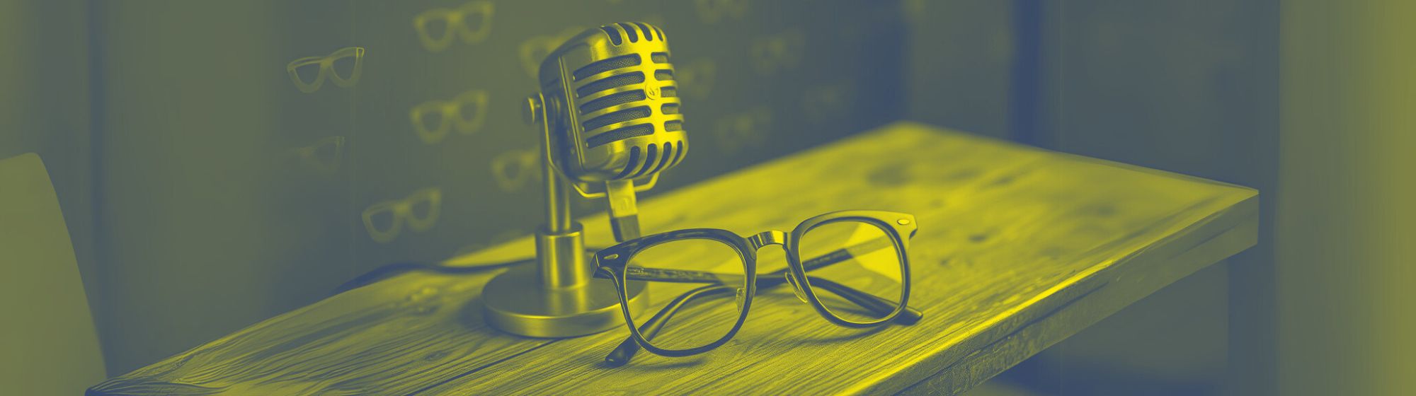Microphone vintage et lunettes posées sur un bureau en bois avec un fond flou et teinté de jaune sur fond bleu