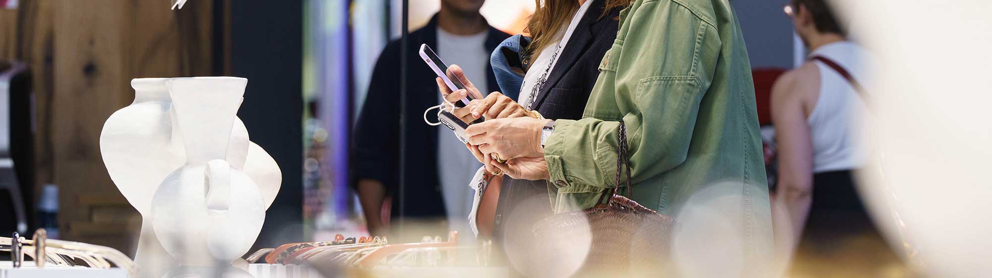 Deux femmes regardant leur téléphone lors d'une exposition de lunettes
