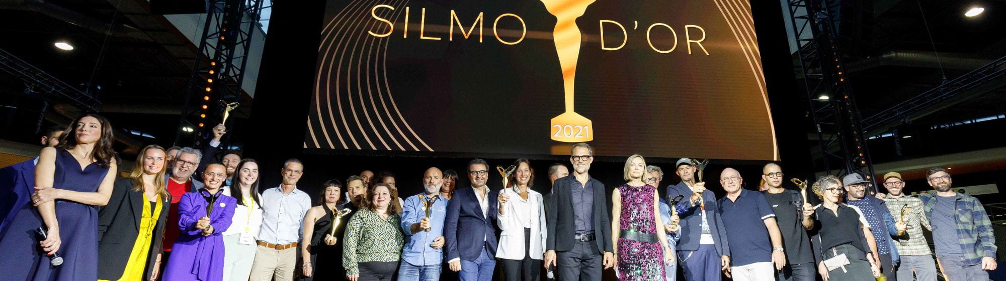 Hommes et femmes, lauréats des SILMO d'Or 2021, soulevant leurs trophées en l'air