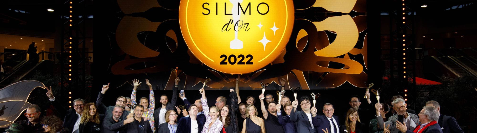 Hommes et femmes, lauréats des SILMO d'Or 2022, soulevant leurs trophées en l'air
