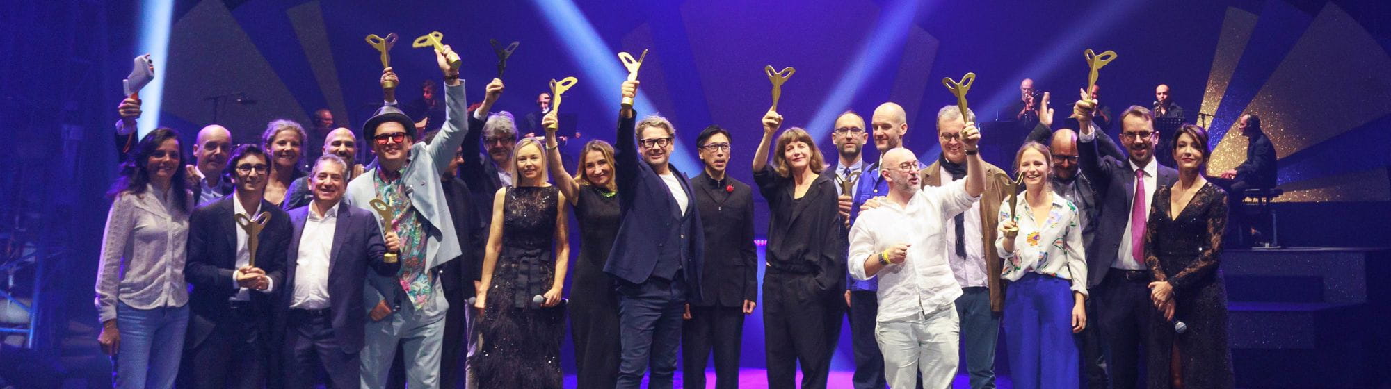 Hommes et femmes, lauréats des SILMO d'Or, soulevant leurs trophées en l'air
