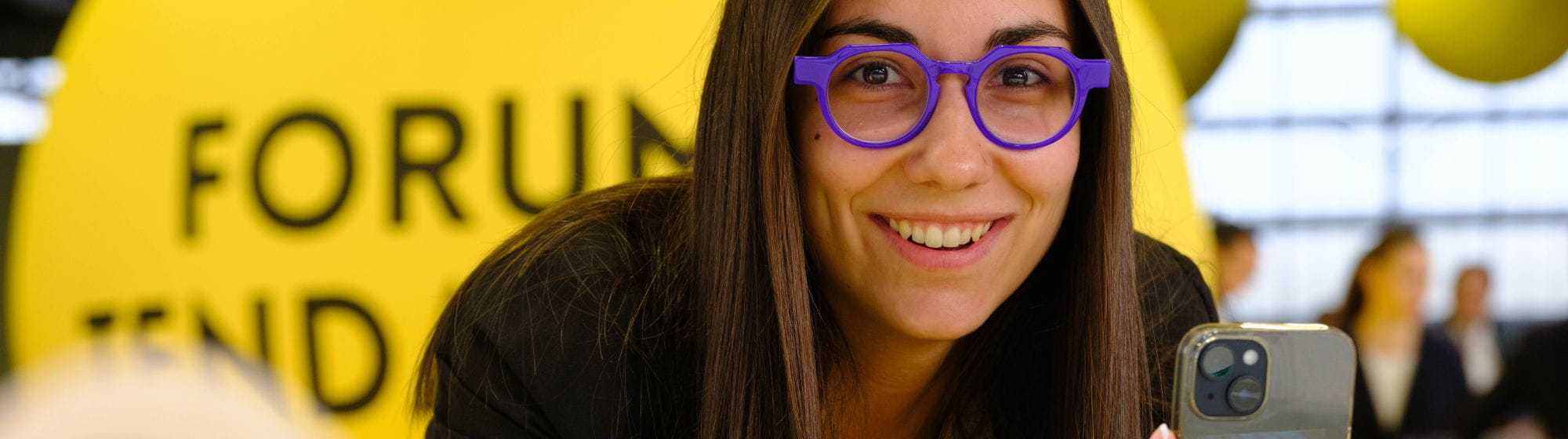 Femme avec des lunettes violettes prenant des photos des dernières tendances au Forum des Tendances du SILMO Paris
