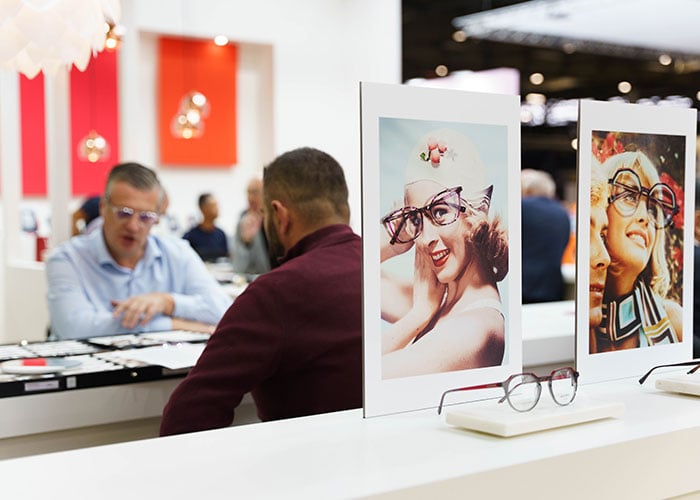 A conversation between an exhibitor and a visitor looking at glasses