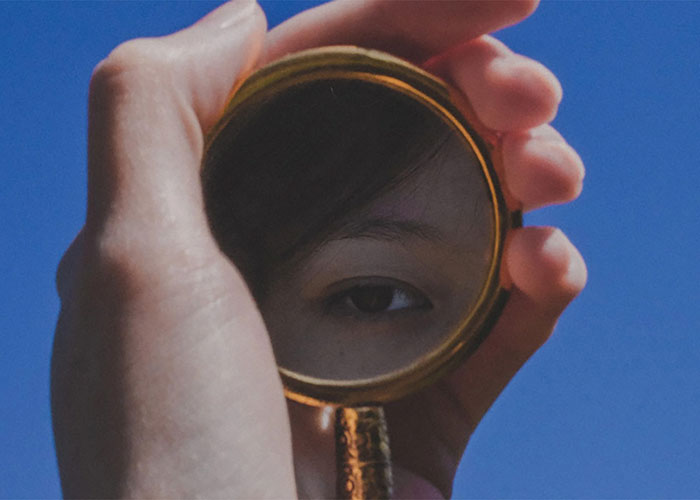 Hand holding a magnifying glass