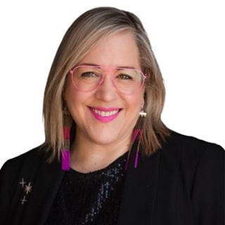 Portrait of a smiling blonde woman with pink glasses, nominee for the International Optician of the Year Award 2025