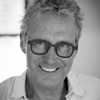 Black & white portrait of a smiling man with distinctive glasses, nominee for the International Optician of the Year Award 2025