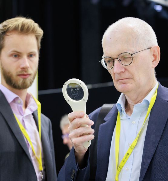 2 men trying out an optical measuring device at SILMO Paris